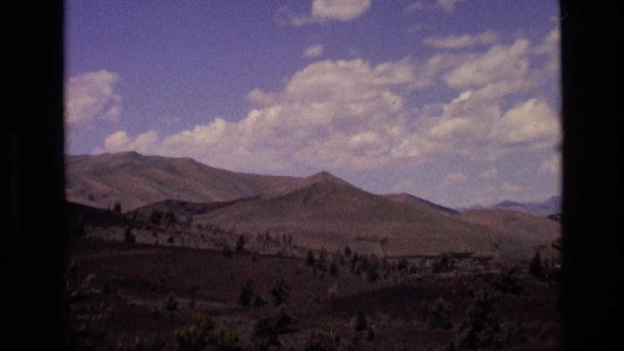 1972 Idaho 8mm frame showing rolling mountain ridges and sparse trees viewed through a dark window frame.