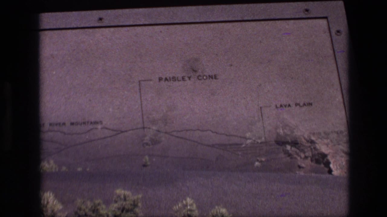 1972 Idaho 8mm frame where the labeled geology diagram appears over or beside the landscape view of a volcanic hill and lava plain.