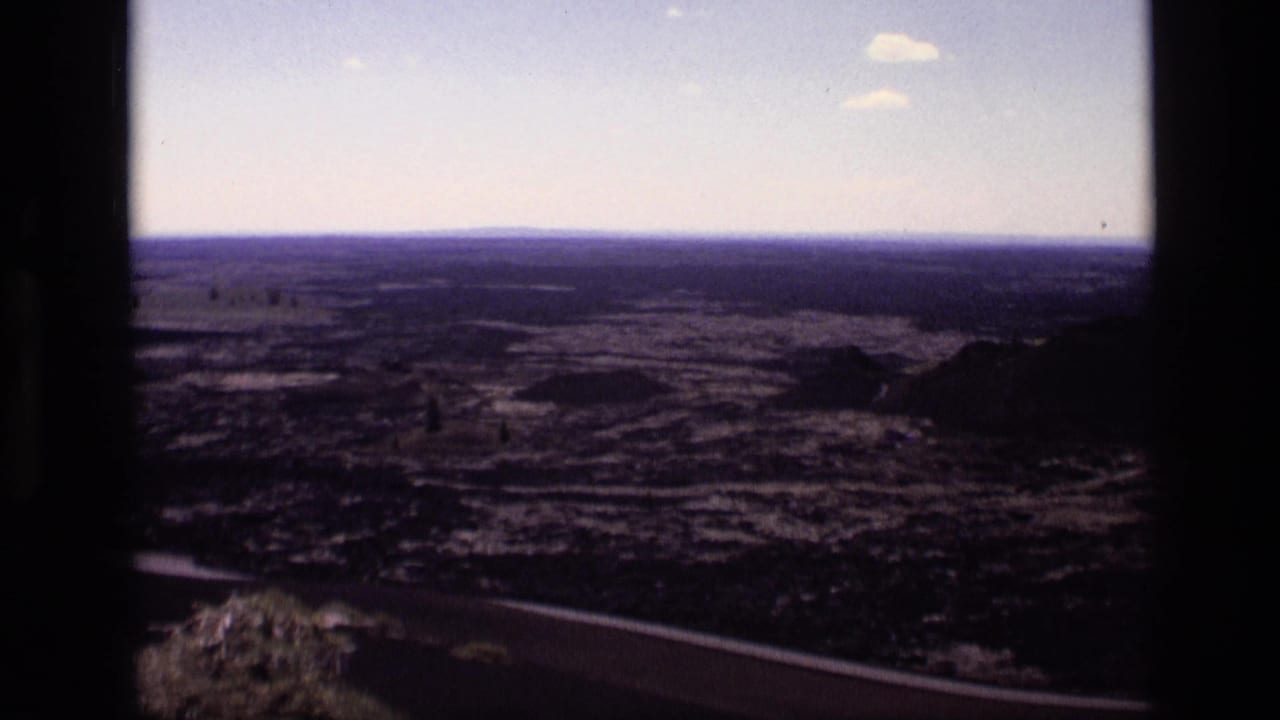 1972 Idaho home-movie frame showing a broad dry landscape from a high vantage point, bordered by dark window or vehicle edges.