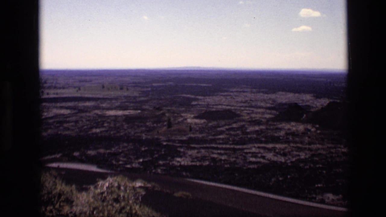 1972 Idaho 8mm frame of open rural terrain and scattered trees, filmed from a high viewpoint with dark edges in the frame.