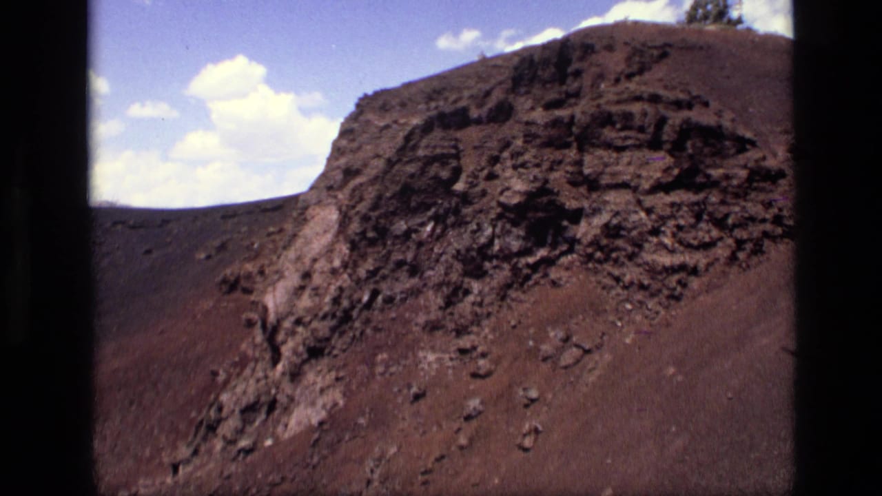 Steep volcanic rock formation with loose stones on a barren slope.