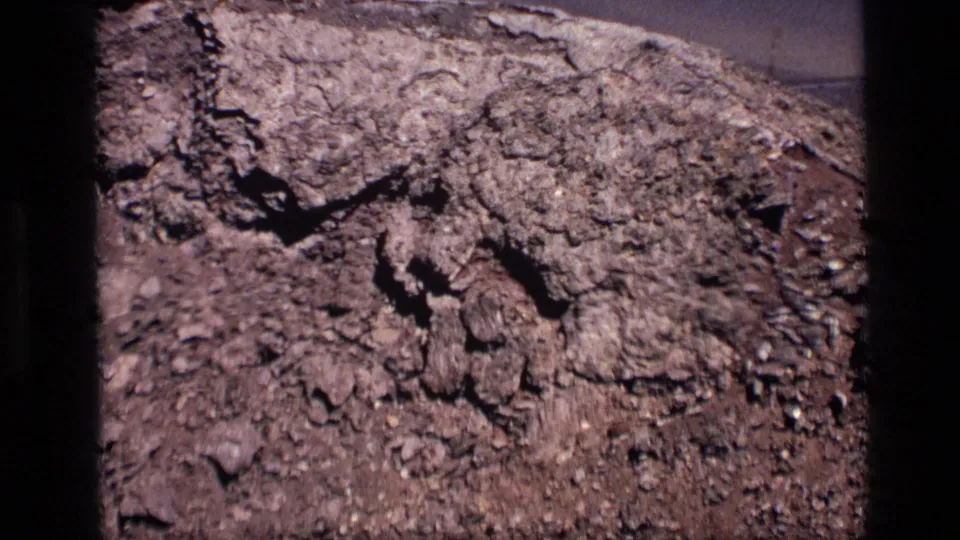 1972 Idaho 8mm close view of cracked ground, loose soil, and dark rock shadows during the slow zoom.