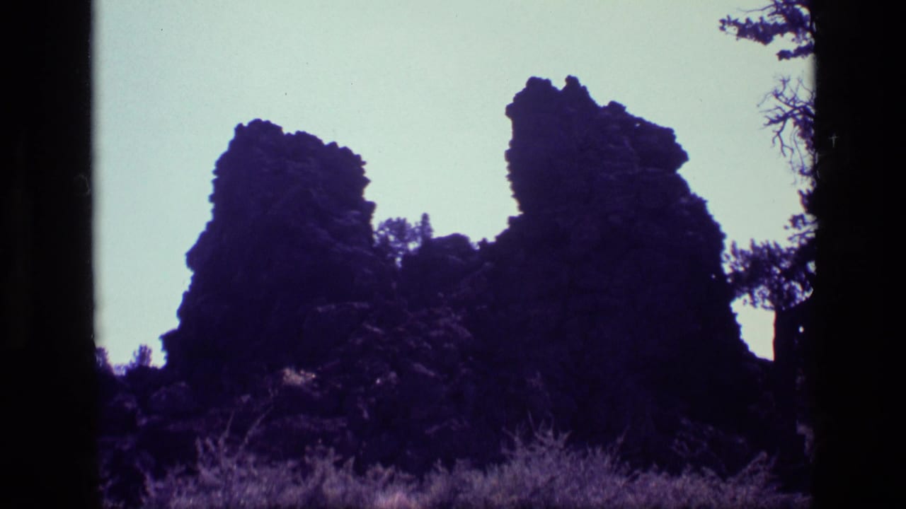 Dark rock formations silhouetted against a pale sky with scrub vegetation below.