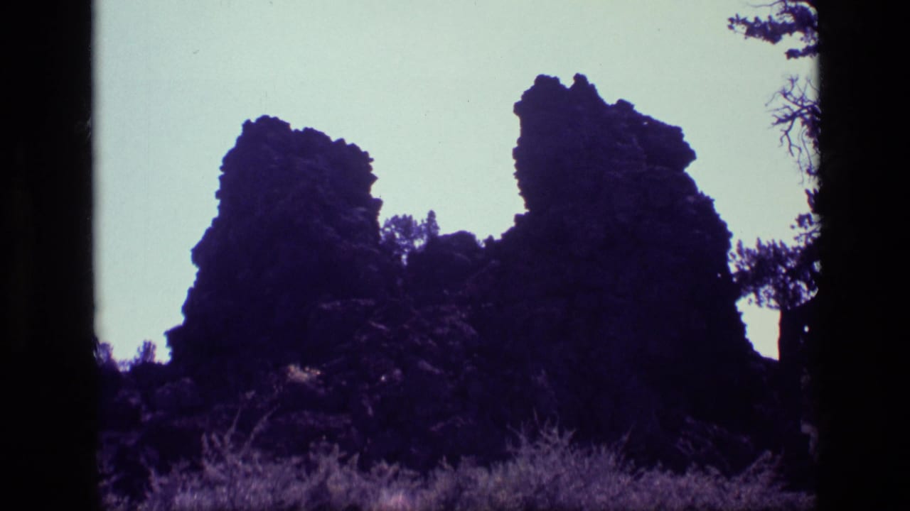 Dark rock outcrops and brush framed by tree silhouettes at the edge.