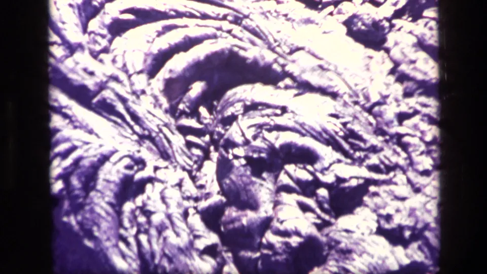 Close 8mm view of ridged volcanic-looking rock texture in Idaho, with bright exposure and purple-blue film color cast.