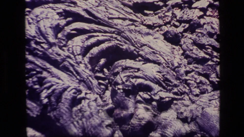 1972 Idaho 8mm close-up of hardened, ridged rock formations with scattered stones and shadowed grooves.