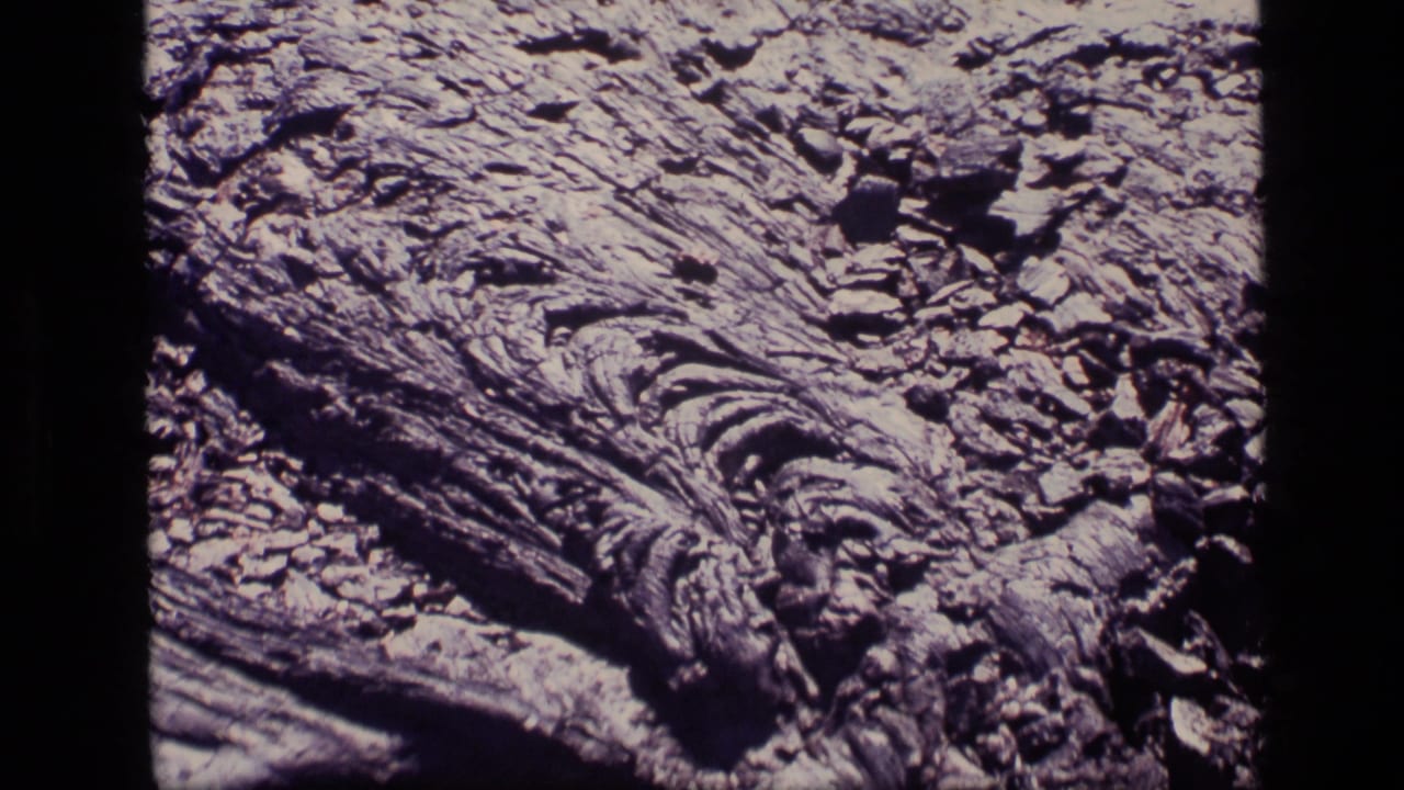 1972 Idaho 8mm frame showing a bark-like natural surface with craggy ridges, dark cracks, and scattered fragments.
