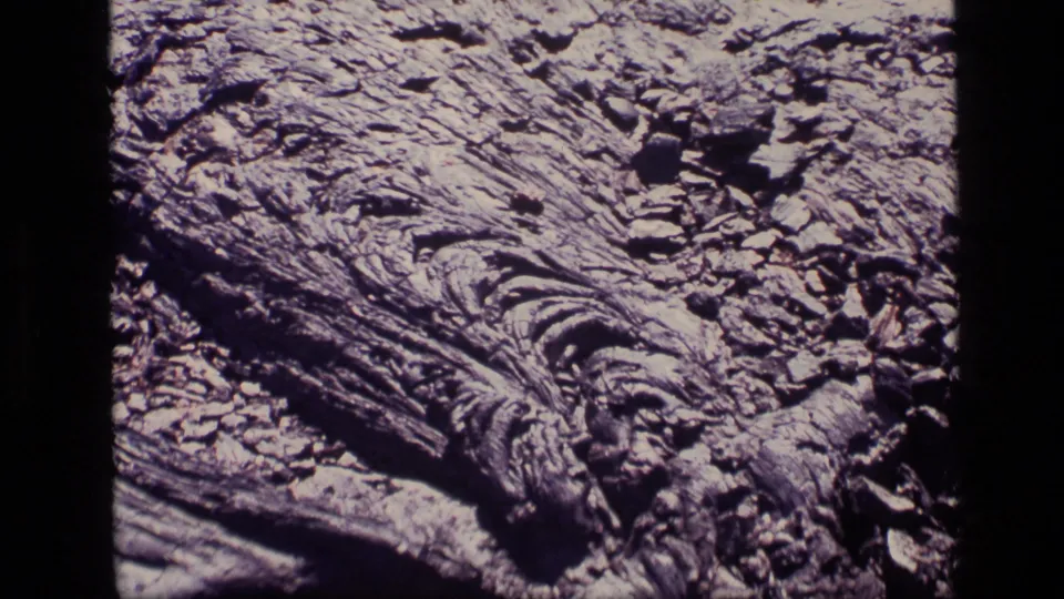 1972 Idaho 8mm frame showing a bark-like natural surface with craggy ridges, dark cracks, and scattered fragments.