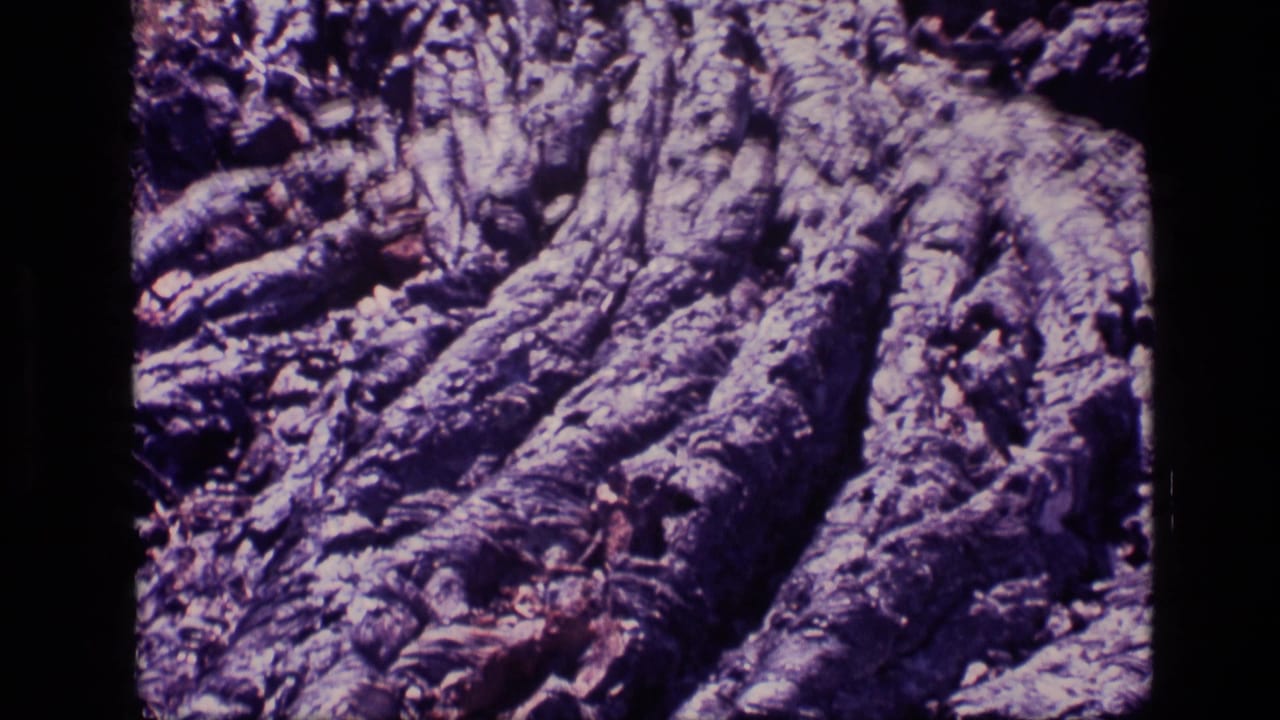 1972 Idaho 8mm frame showing a tight view of rugged, eroded rock with deep grooves and purple aged-film color.