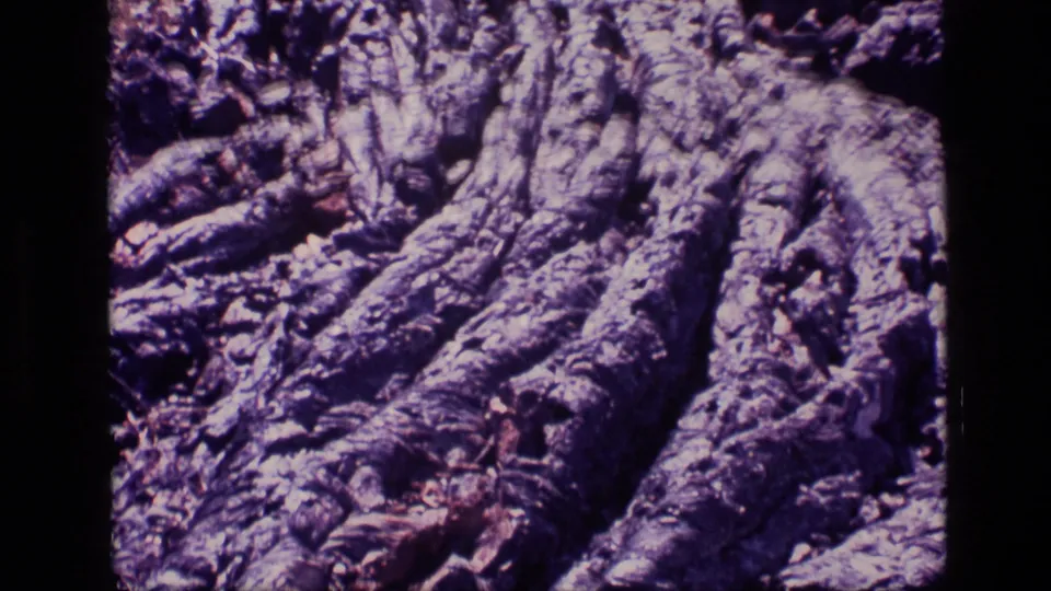 1972 Idaho 8mm frame showing a tight view of rugged, eroded rock with deep grooves and purple aged-film color.