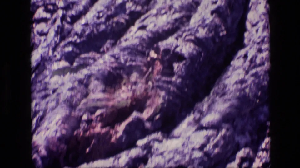 Close 8mm view of Idaho rock formations, with rough ridges, broken surfaces, and shadowed openings in the stone.