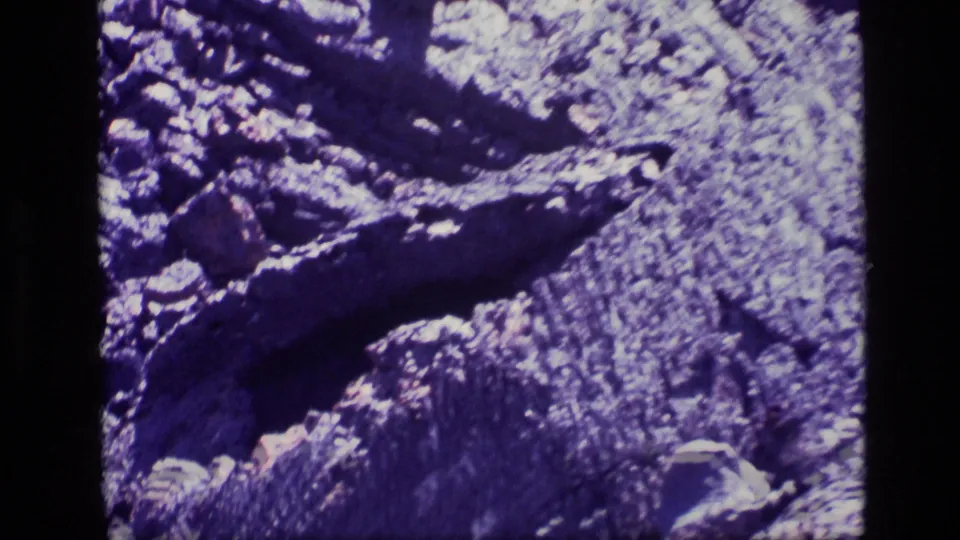 1972 8mm frame from Idaho showing a close rocky surface, ridged stone texture, scattered rocks, and high-contrast daylight exposure.