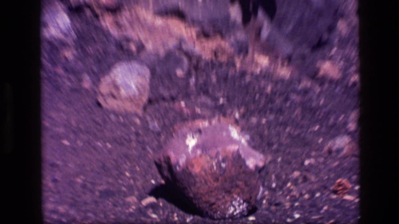 Blurred close-up of a small dark rock on rough ground.