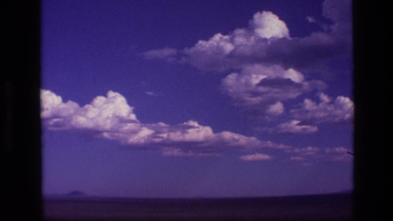 Clouds over a dark flat horizon seen through vehicle-window edges.