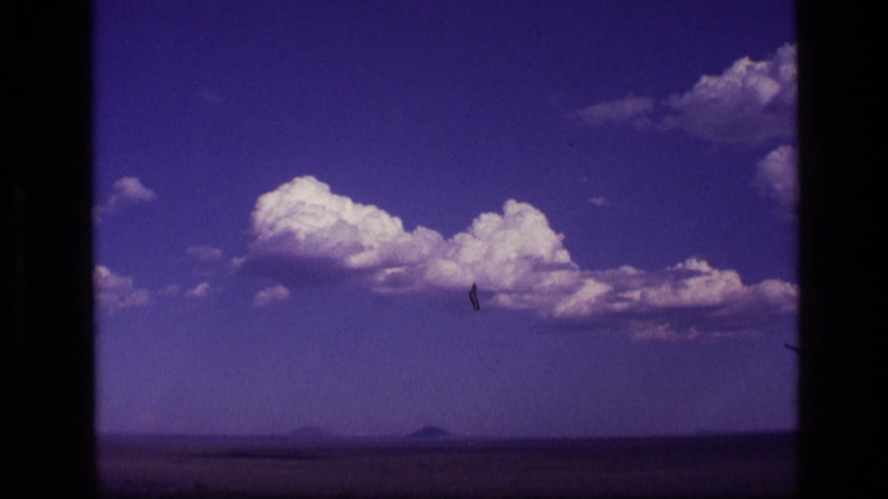 Bright clouds above open land with a small distant mountain shape.