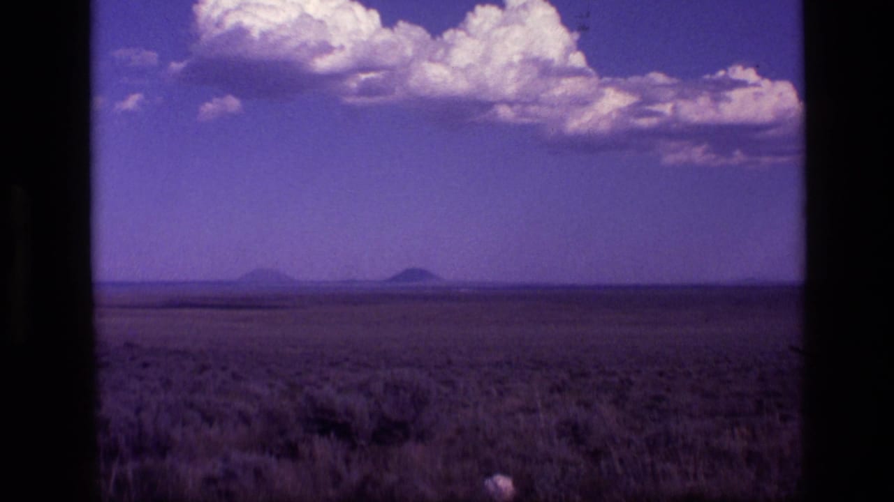 1972 Idaho 8mm frame showing open desert scrub, distant volcanic-looking hills, purple sky, and dark window framing.
