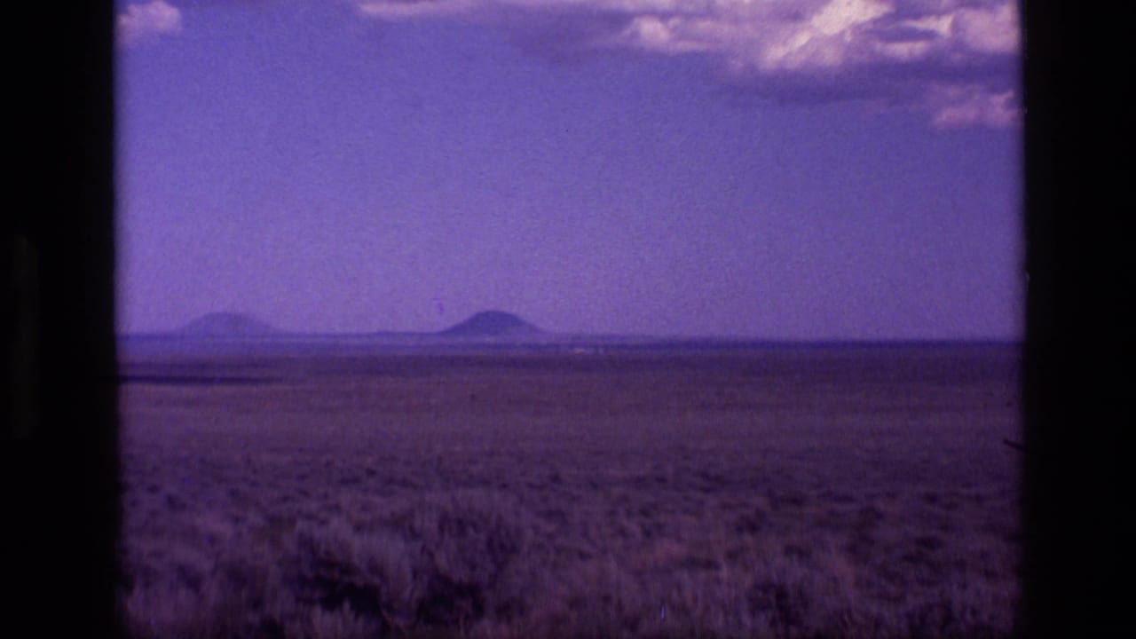 Idaho desert landscape on 8mm film with two distant volcanic-looking forms and a central dark window divider.