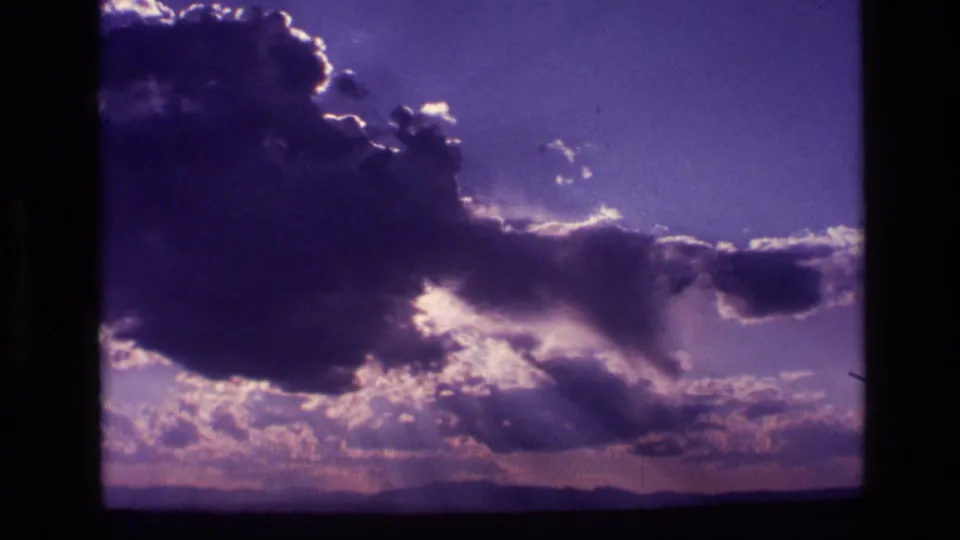 1972 Idaho 8mm frame with a large cloud bank, radiant light rays, and a low dark horizon line.