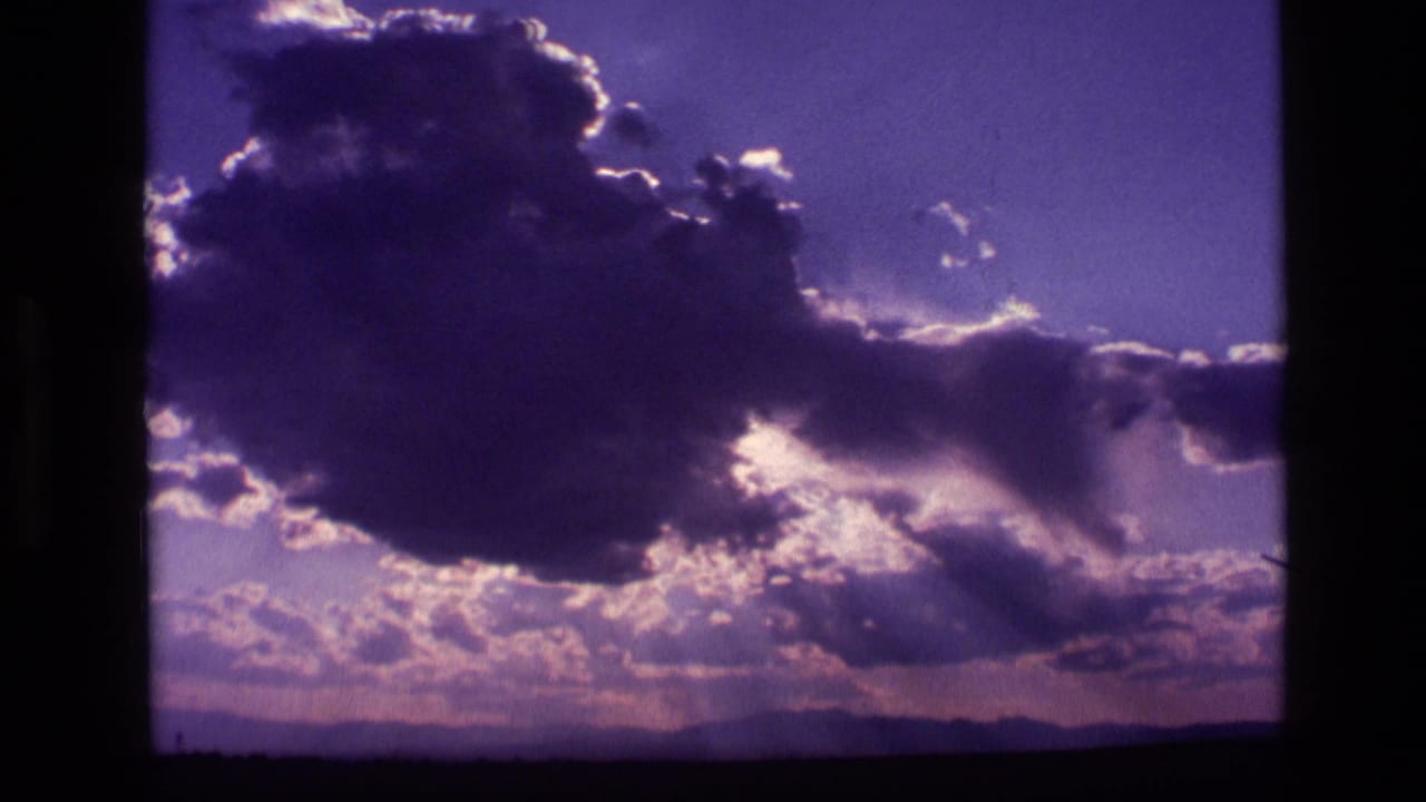 Dark cloud mass over a low horizon with bright sunlight behind the cloud edge.