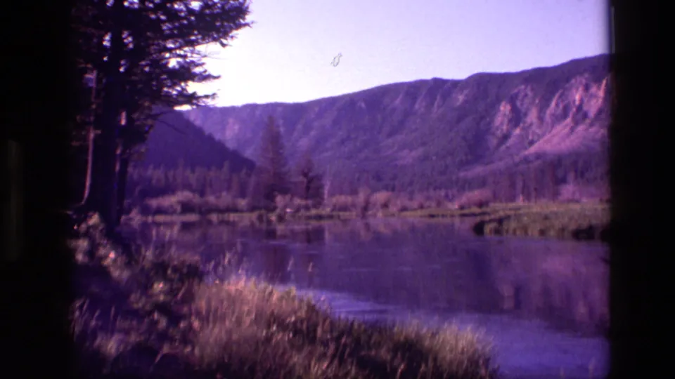Final 1972 Idaho 8mm frame holds on lake water, trees, and a mountain ridge with vintage color cast.