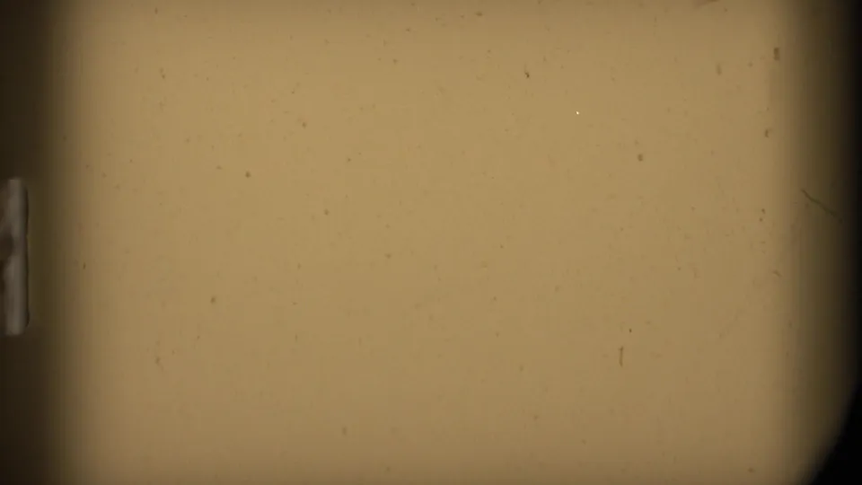 8mm leader or blank exposed film frame with tan color, dark gate edges, and visible dust specks.