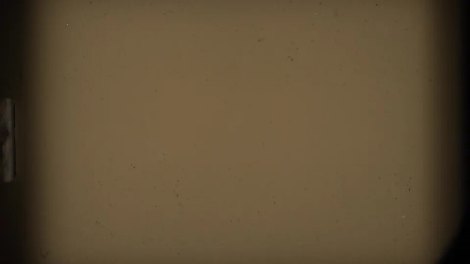 End-frame leader on the 8mm scan, showing tan film surface, rounded dark borders, dust, and slight color variation.