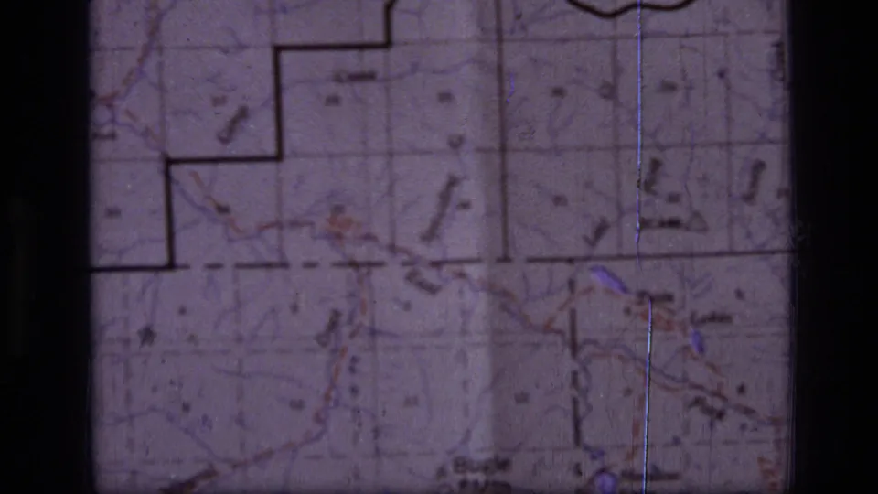 Close-up of a Montana topographic map with route markings and terrain labels, filmed as a 1973 8mm travel-planning cutaway.
