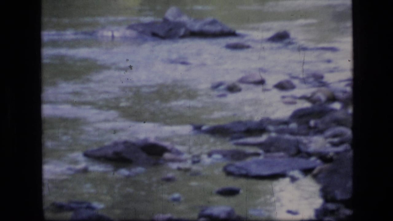 1973 8mm home-movie frame from Scapegoat Wilderness showing a rocky stream with muted color and visible film wear.