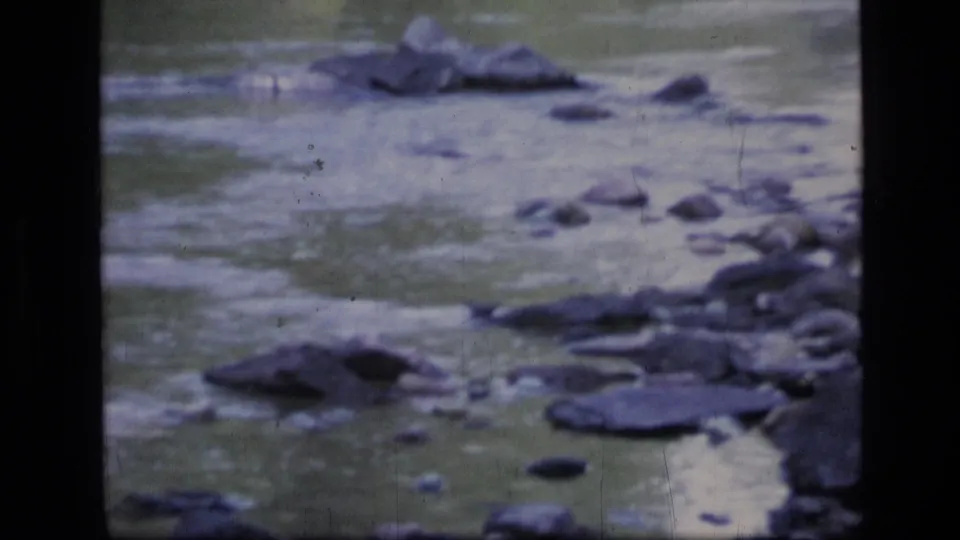 1973 8mm home-movie frame from Scapegoat Wilderness showing a rocky stream with muted color and visible film wear.