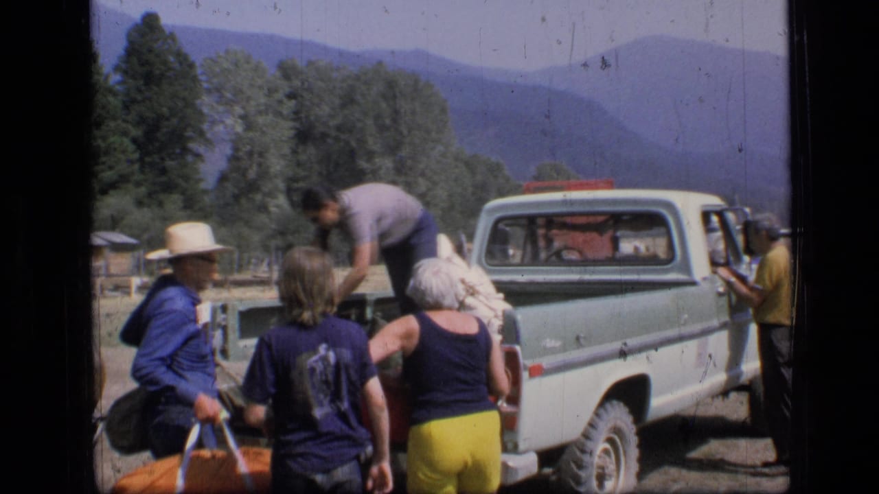 1973 Scapegoat Wilderness home-movie frame showing adults unloading camping gear from a light pickup truck in a mountain meadow.