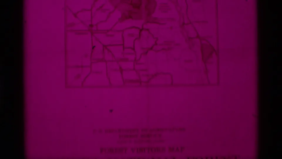 1975 8mm frame showing a magenta-tinted close-up of a Sierra National Forest visitors map with faint labels and border lines.