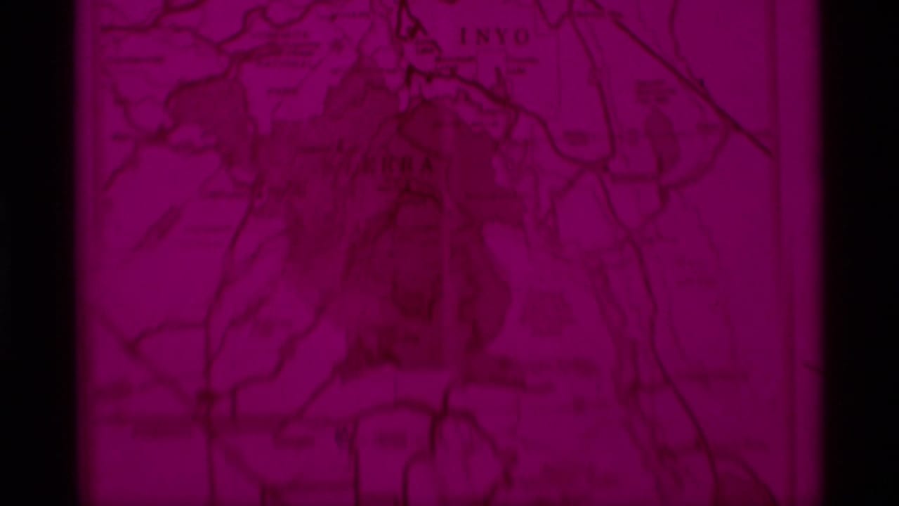 A soft 8mm frame shows the visitors map in heavy magenta color shift, with roads or boundaries and faint California region labels.