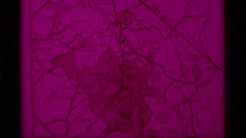 Magenta-faded 8mm frame of the lower visitors map, where Inyo and Nevada labels appear amid roads and boundary markings.
