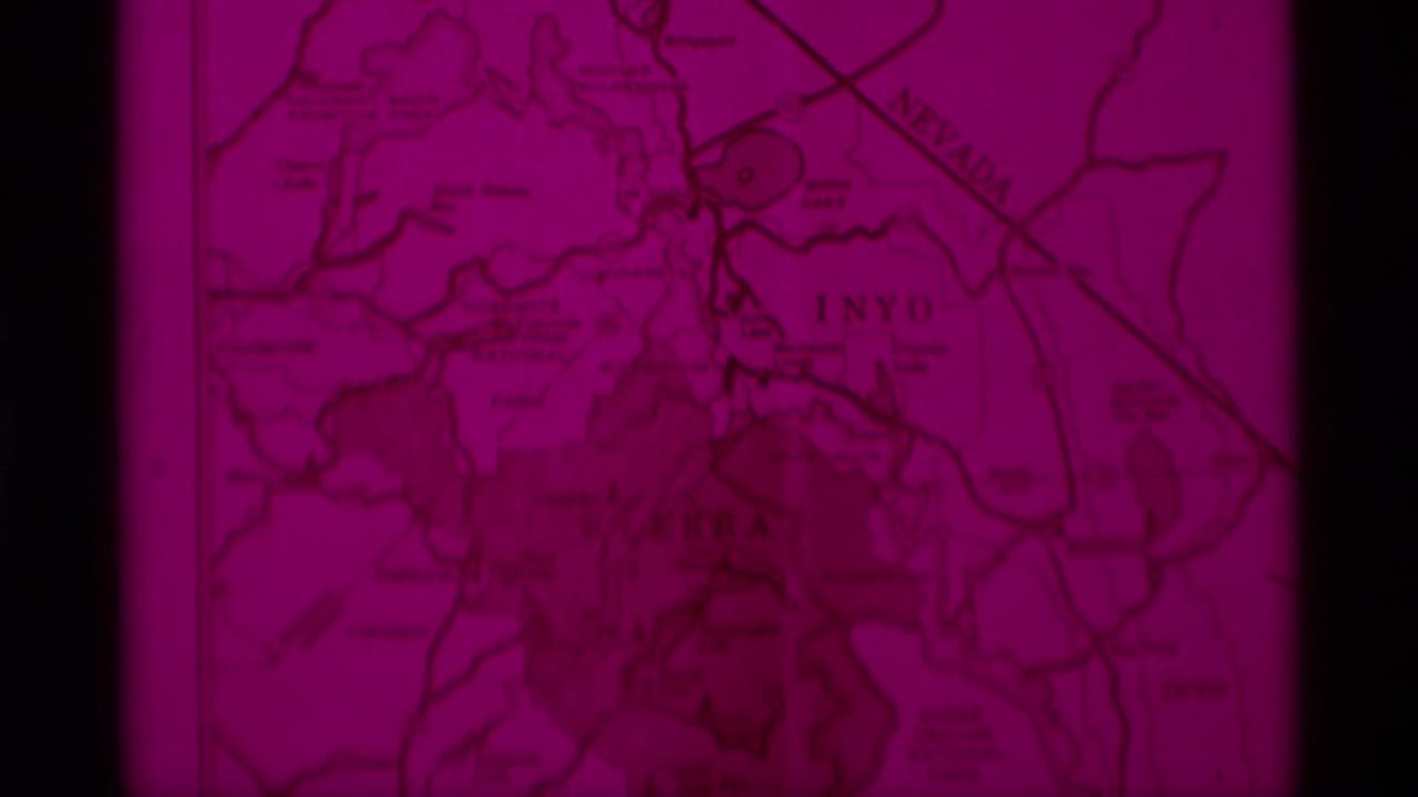 Red-tinted topographical map frame from 1975 8mm Minaret Wilderness travel footage, with Sierra Nevada regional markings partly visible.