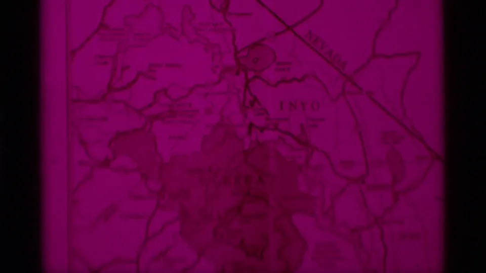 Red-tinted topographical map frame from 1975 8mm Minaret Wilderness travel footage, with Sierra Nevada regional markings partly visible.