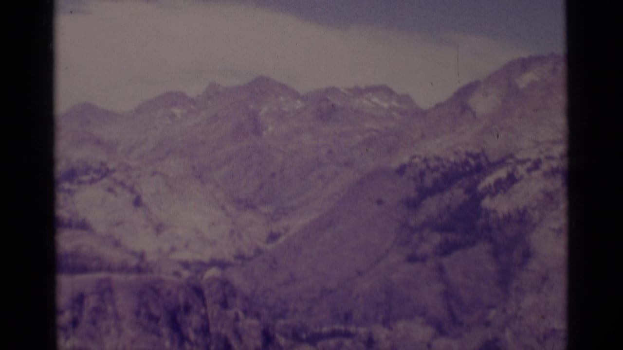 1975 Minaret Wilderness landscape with layered ridgelines, scattered snow, pale sky, and soft aged-film color.