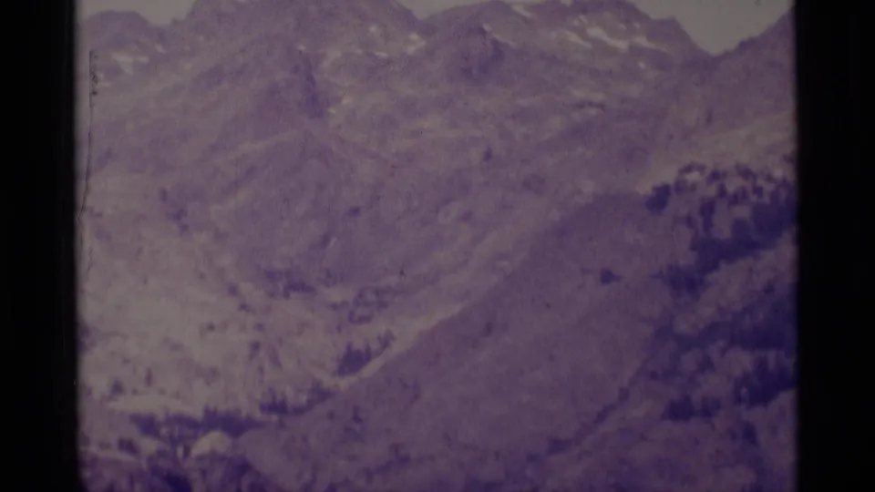 1975 8mm mountain slope view in the Minaret Wilderness, showing rocky terrain, sparse trees, and purple faded color.