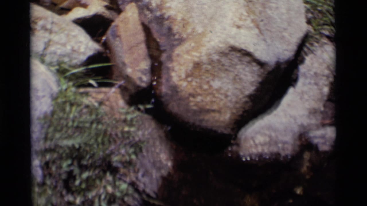 Close 8mm frame of a narrow stream passing around weathered rocks in Minaret Wilderness, California.