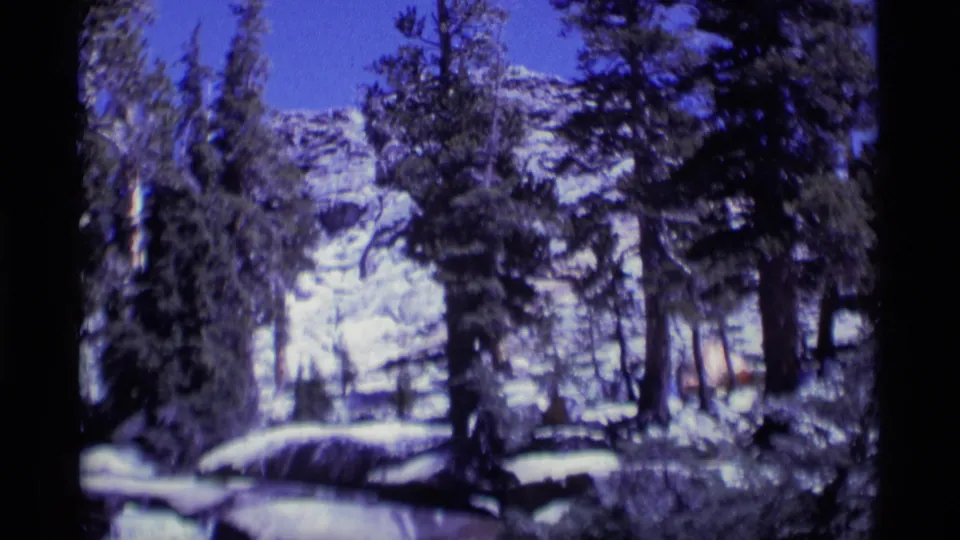 Snow-dusted evergreens and rocky mountain terrain in Minaret Wilderness, California, filmed on 8mm in 1975.