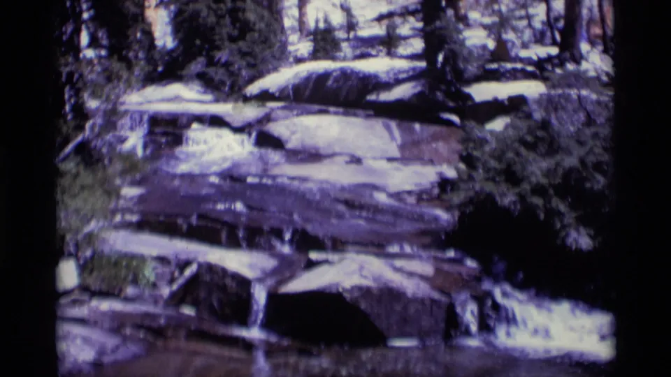 Minaret Wilderness forest water feature with pale cascades crossing dark layered rock in aged 8mm color.