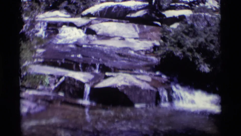 Vintage 8mm view of a small cascade dropping from layered rocks into a shaded pool in Minaret Wilderness.