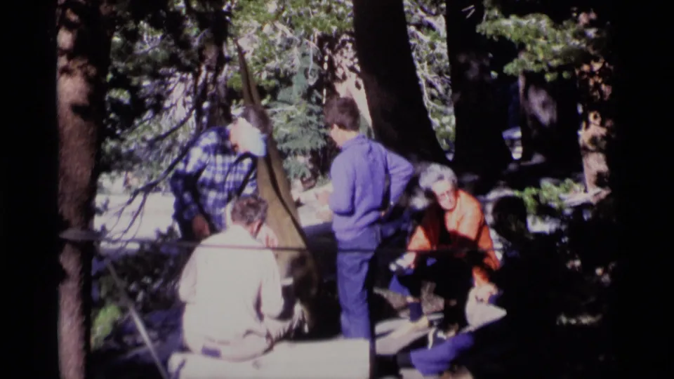 1975 forest gathering frame with a plaid-shirted adult leaning near seated companions in Minaret Wilderness.