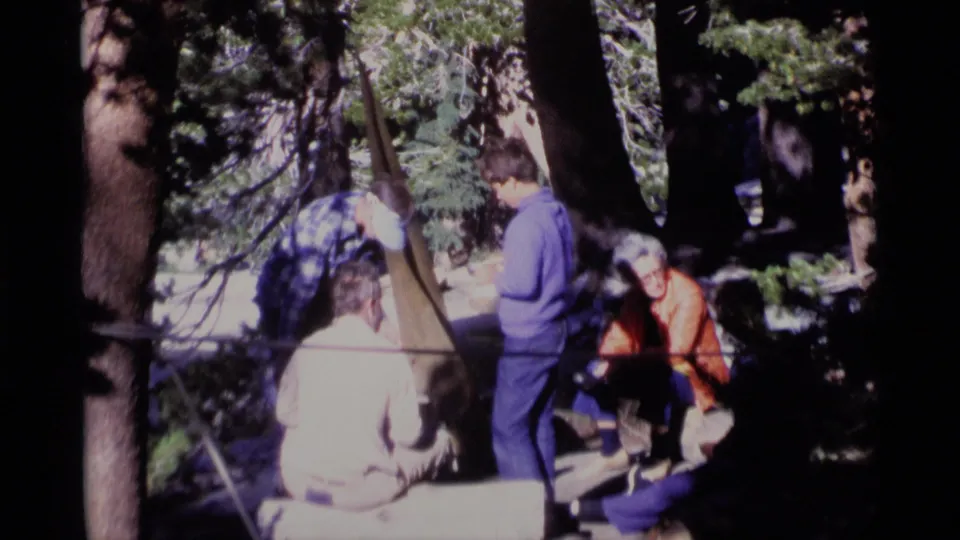 Minaret Wilderness 8mm frame showing adults in casual outdoor clothing gathered under trees in 1975.