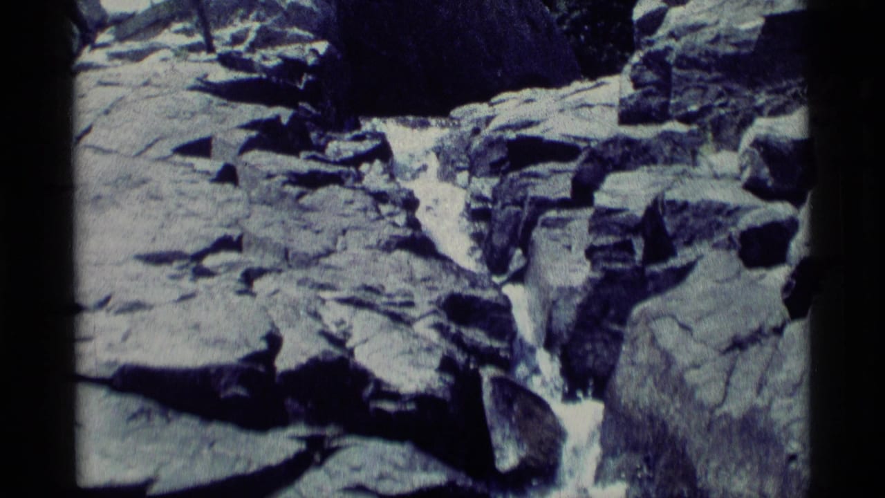 Rocky stream channel with white water flowing over gray stones.