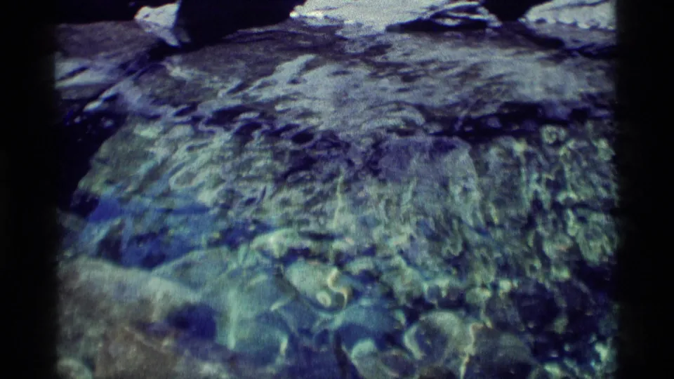 The final frame looks down at clear rippling water and submerged stones below the rocky stream in Minaret Wilderness.