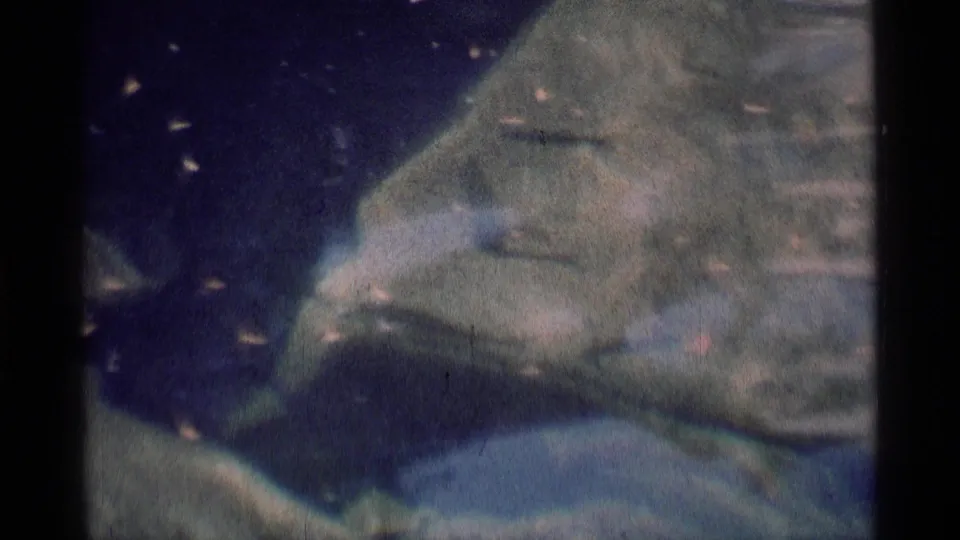1975 8mm Minaret Wilderness close-up showing water curving around a large pale rock with mossy green edges and soft film texture.