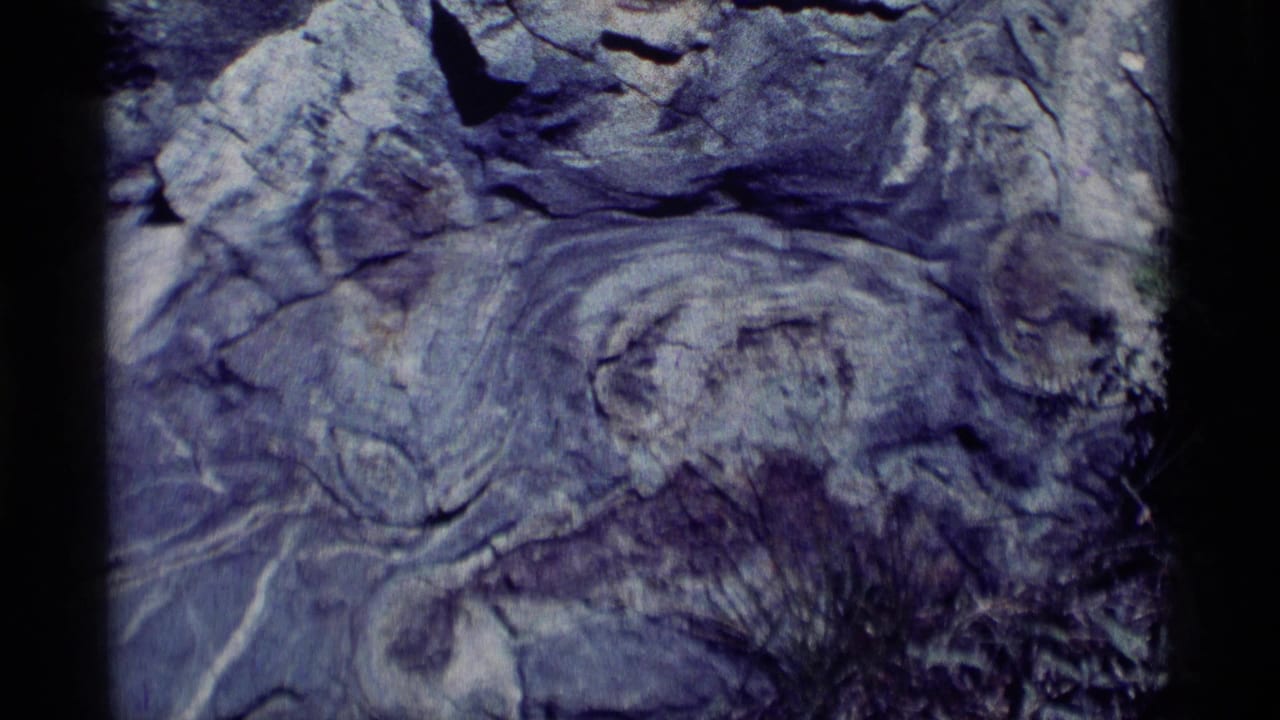 Close view of a gray-blue fissured boulder with layered rock texture and shadowed cracks.