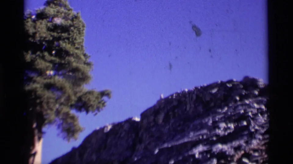 Wide 8mm view of a tree and rugged mountain slope beneath blue sky in the Minaret Wilderness area.