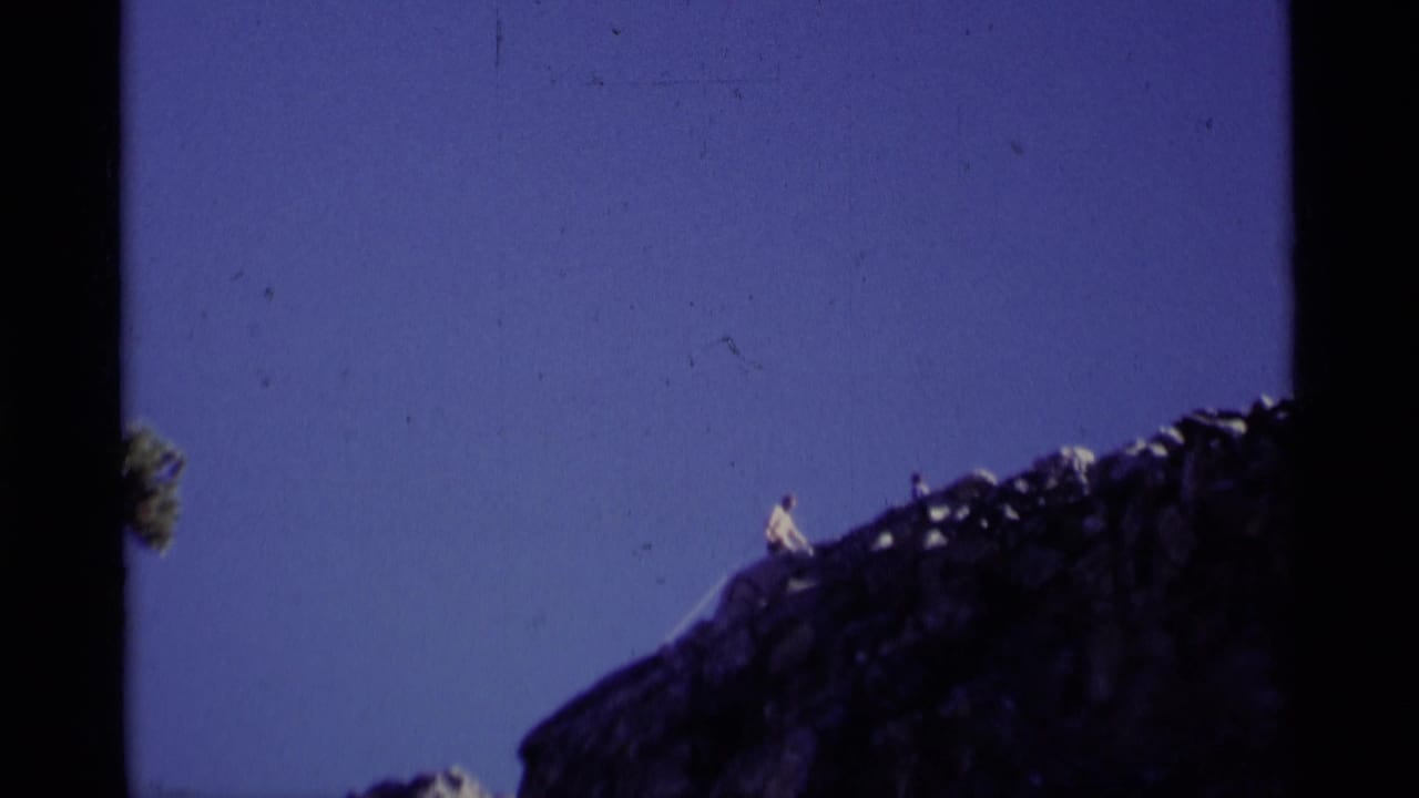 Distant hiker standing on a rocky ridge against a blue sky.