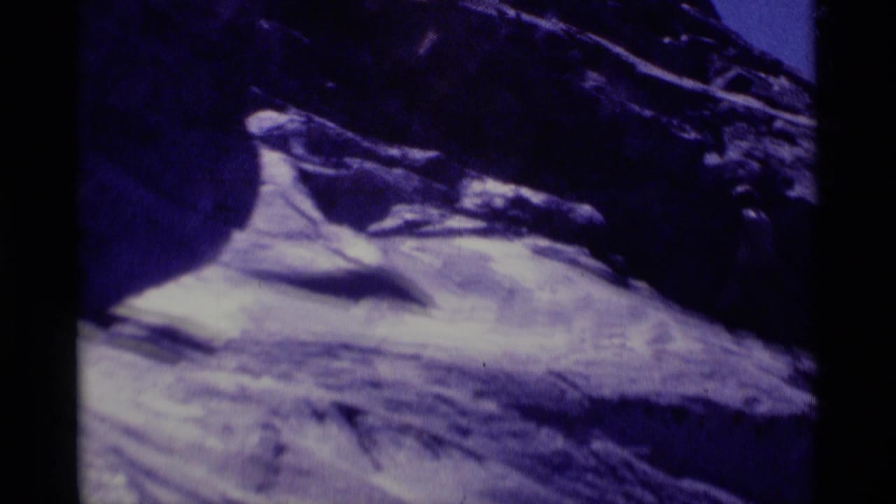 1975 Minaret Wilderness frame with a pale snowlike or stone surface below dark rugged rocks, seen through soft 8mm exposure.